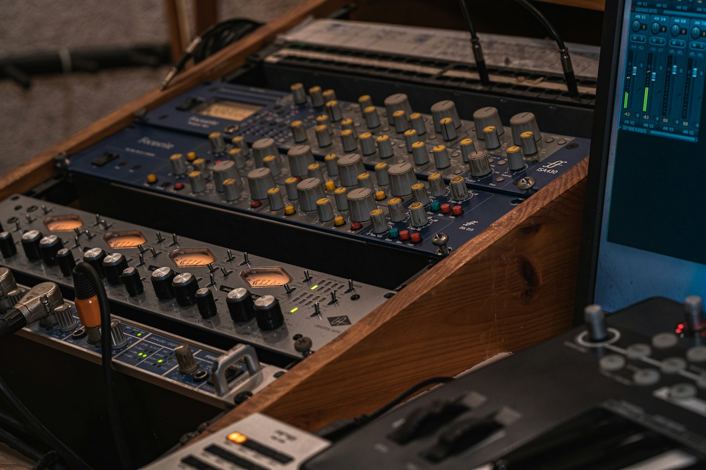 Du matériel de mixage audio professionnel se trouve dans un rack en bois.