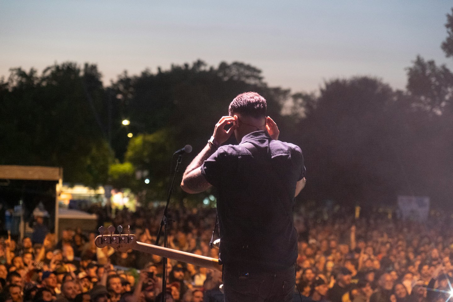Un musicien ajuste ses retours intra-auriculaires sur scène devant un public.