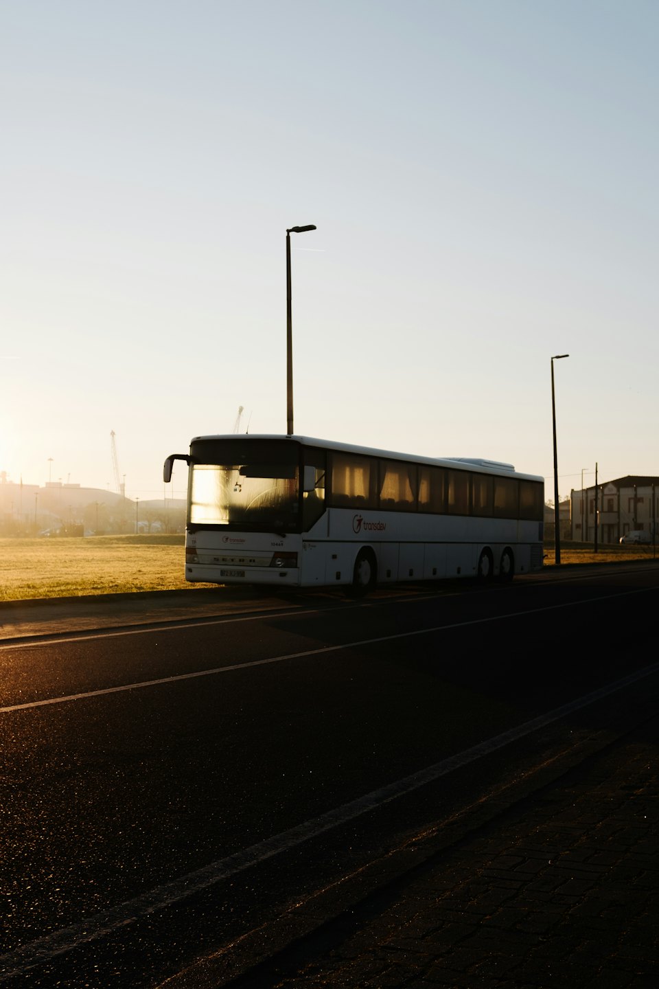 Bus touristique blanc garé au bord de la route au lever ou au coucher du soleil.